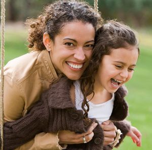Mother holding daughter on swing