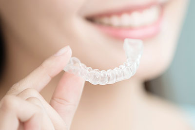 a smiling woman holding clear braces