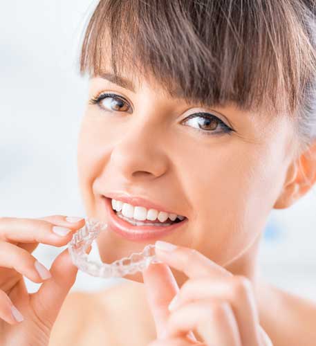 brunette woman with bangs holding clear whitening tray