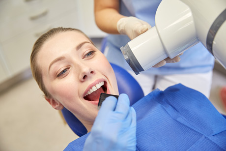 young woman with pony tail lying in dental chair, getting X-rays taken