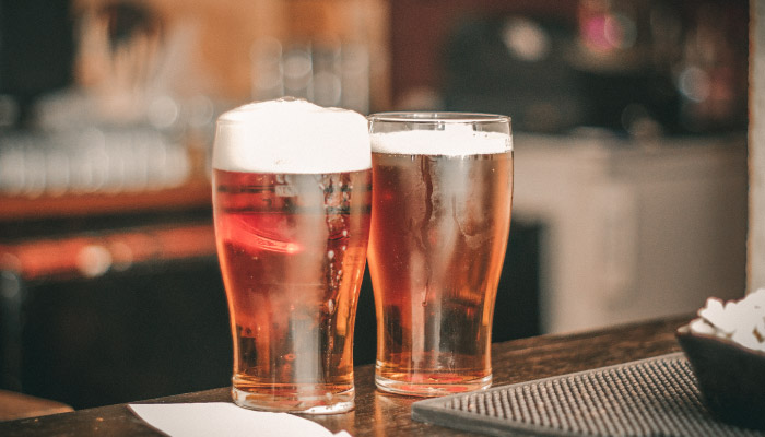 two glasses of beer on a bar counter